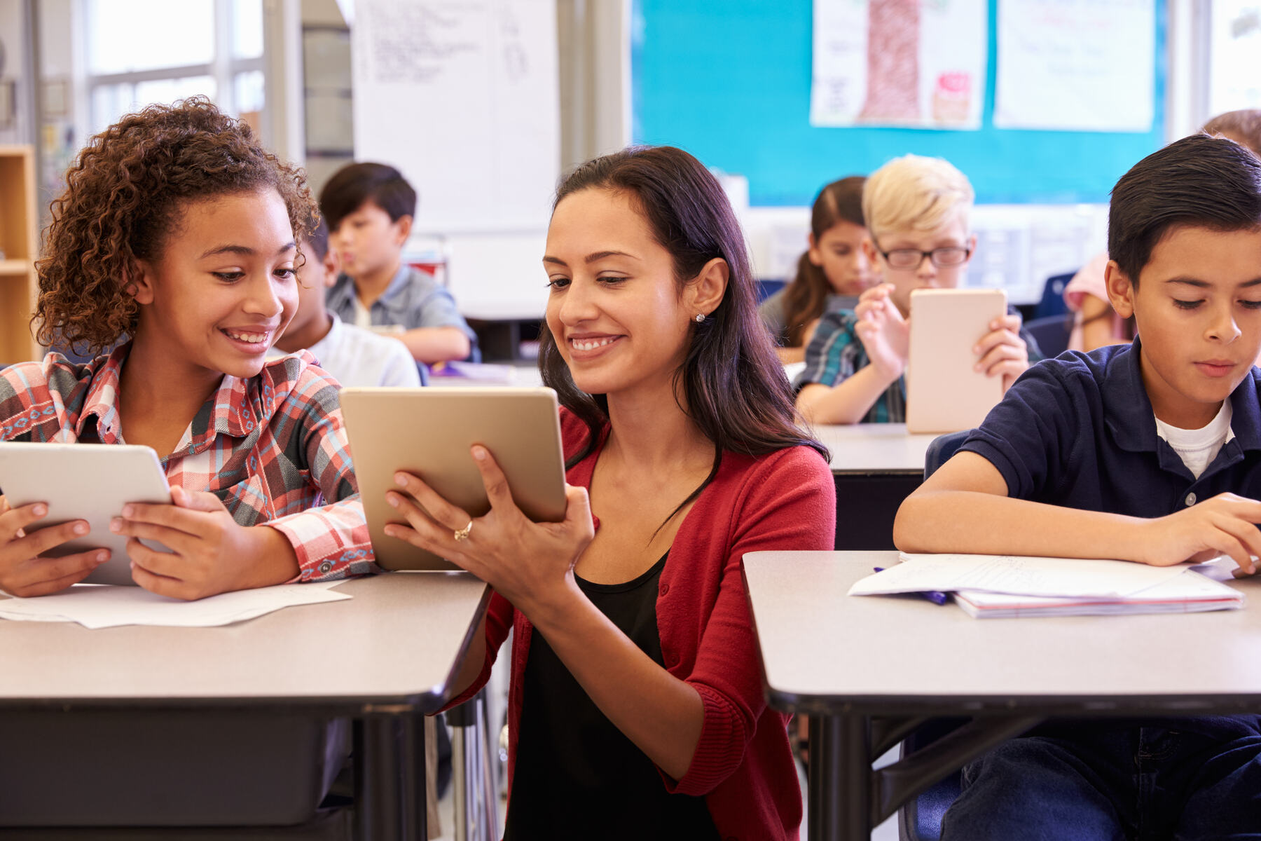 Teacher working with elementary students on tablets