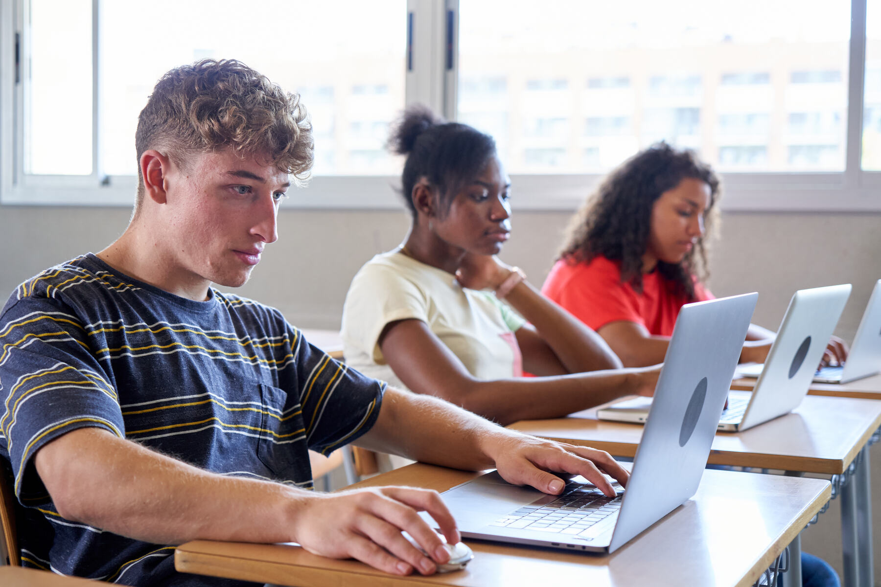 Teenage students studying on laptops in a classroom